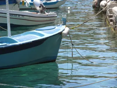 a boat tied to a dock in the water at Nikolitsi Studios in Symi