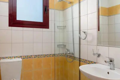 a bathroom with a shower and a toilet and a sink at Cicada Villa in Koskinou
