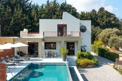a villa with a swimming pool in front of a house at Cicada Villa in Koskinou