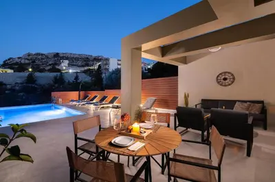 a patio with a table and chairs and a pool at Cicada Villa in Koskinou