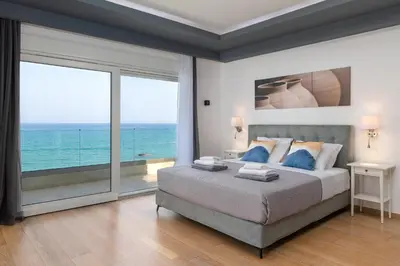 a bedroom with a bed with a view of the ocean at Hamilton Sea Front Villa in Archangelos