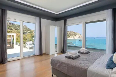 a bedroom with a bed with a view of the ocean at Hamilton Sea Front Villa in Archangelos