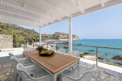 a wooden table and chairs on a balcony with the ocean at Hamilton Sea Front Villa in Archangelos