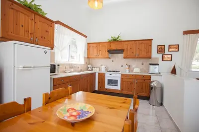 a kitchen with a table with a bowl of fruit on it at The Olive Grove Villa Private Pool with Sea & Sunset Views in Theologos