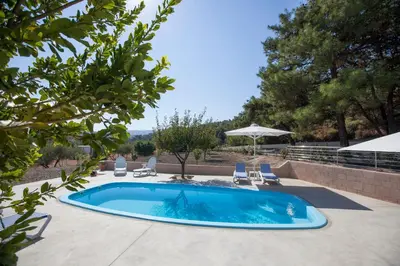 a swimming pool with chairs and an umbrella at The Olive Grove Villa Private Pool with Sea & Sunset Views in Theologos