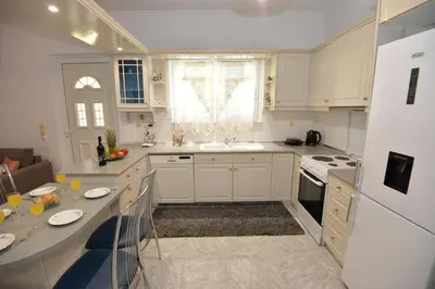 a kitchen with white cabinets and a table in it at Nina's Apt in Ialysos near the Beach in Ialyssos