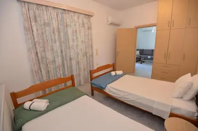 two beds in a small room with a window at Nina's Apt in Ialysos near the Beach in Ialyssos