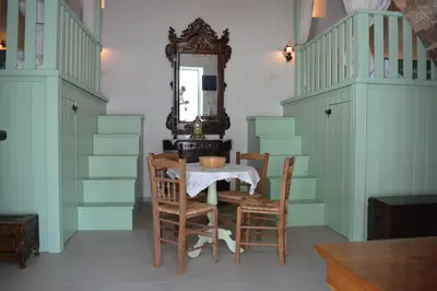 a dining room with a table and chairs and a mirror at The Priest's Traditional House Kalithies in Kalithies