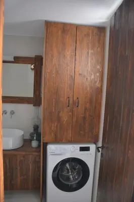 a kitchen with a washing machine and a wooden cabinet at The Priest's Traditional House Kalithies in Kalithies