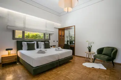 a bedroom with a bed and a green chair at Rodi Luxury Apartment in Rhodes Town