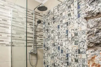 a bathroom with a shower with a tile wall at Kalimera Villa By the Sea in Gennadi