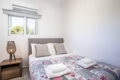 a bedroom with a bed with pillows and a window at Kalimera Villa By the Sea in Gennadi