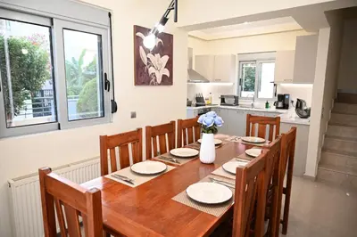 a kitchen and dining room with a wooden table and chairs at Villa De Ella in Ialyssos
