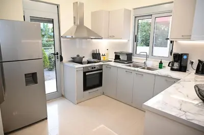 a white kitchen with a sink and a refrigerator at Villa De Ella in Ialyssos