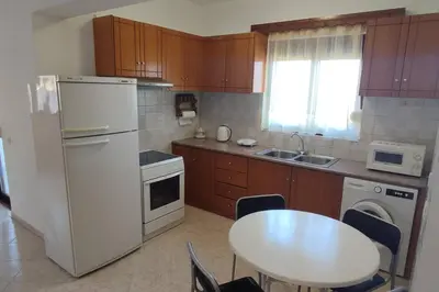 a kitchen with a table and a white refrigerator at Tilos Pearl in Livadia