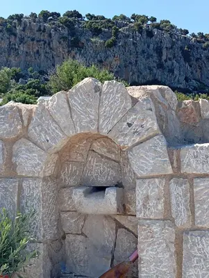 a stone wall with graffiti on it with a mountain in the background at Exclusive Olive & Herb Villa, Mountain to Sea Views, Rhodes in Afantou