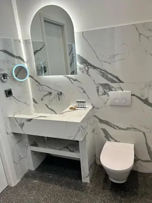 a bathroom with a sink and a toilet and a mirror at Jensen Luxury Suites in Rhodes Town