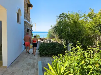 two people walking down a walkway looking at the ocean at George Seaside Serviced Studios & Apartments in Pefki Rhodes