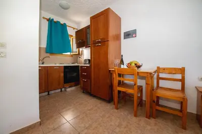 a kitchen with a wooden table and chairs and a sink at George Seaside Serviced Studios & Apartments in Pefki Rhodes