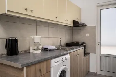a kitchen with a washing machine and a sink at Sokrates Apartments in Kolimbia