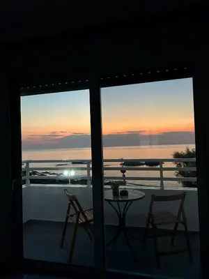 a view of a sunset from a balcony with a table and chairs at Chrisanthi Apartments in Archangelos