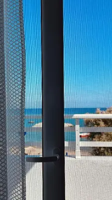 a door with a view of the ocean from a beach at Chrisanthi Apartments in Archangelos
