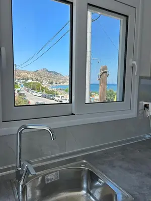 a kitchen sink with a window above a kitchen counter at Chrisanthi Apartments in Archangelos