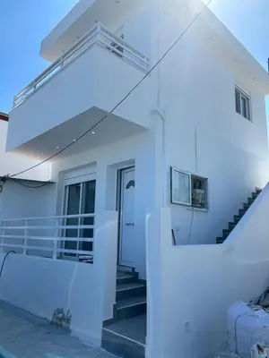 a white house with a staircase and a door at Chrisanthi Apartments in Archangelos
