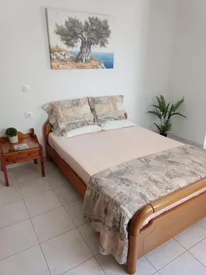 a bedroom with a bed with a tree on the wall at Maria Studios & Apartments in Kremasti