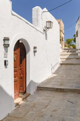 a white building with a wooden door on a street at Villa Nouna in Líndos