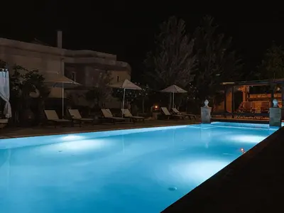 a swimming pool at night with chairs and umbrellas at Theonia Villas in Pefki Rhodes