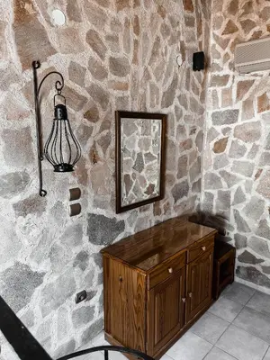 a stone wall with a wooden cabinet and a lamp at Theonia Villas in Pefki Rhodes