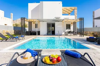 a swimming pool with a table with a bowl of fruit on it at Villa Livis 2 in Kiotari
