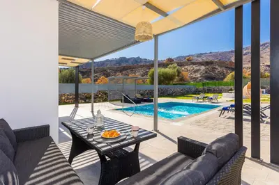 a patio with a couch and a table and a pool at Villa Livis 2 in Kiotari