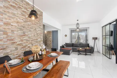a living room with a wooden table and a brick wall at Villa Livis 2 in Kiotari