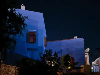 a white building with a window at night at Symi Uptown Indigo in Symi