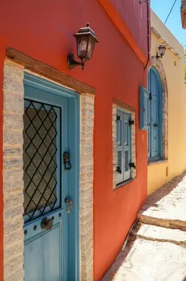 an orange building with a blue door and a lamp at Symi Uptown Carmine in Symi