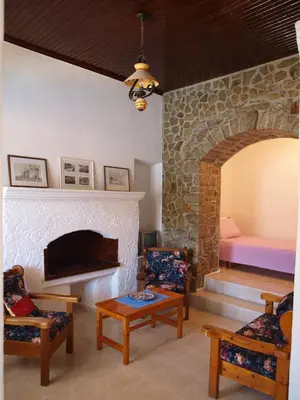 a living room with a fireplace with chairs and a bed at Marina Studios in Symi
