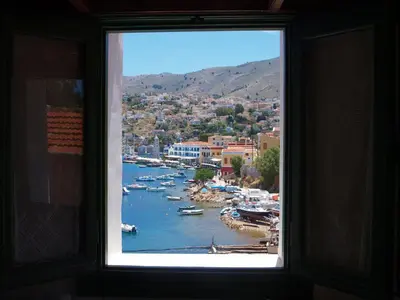 a window with a view of a harbor with boats at Marina Studios in Symi