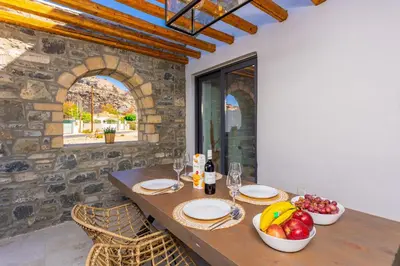 a wooden table with bowls of fruit and wine glasses at La Casa Di Pietre 1 in Kiotari