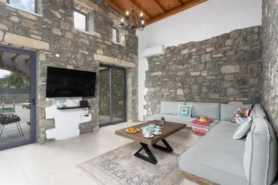 a living room with a stone wall at La Casa Di Pietre 3 in Kiotari