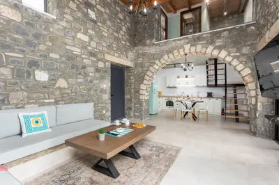 a living room with a stone wall and a table at La Casa Di Pietre 3 in Kiotari