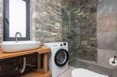 a bathroom with a sink and a washing machine at La Casa Di Pietre 3 in Kiotari