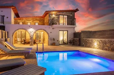 a villa with a swimming pool in front of a house at La Casa Di Pietre 3 in Kiotari