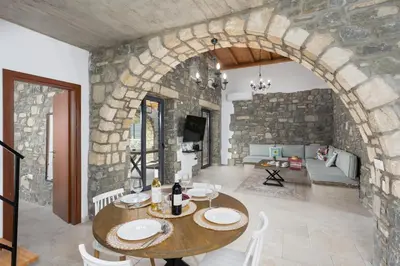 a living room with a table and a stone wall at La Casa Di Pietre 3 in Kiotari