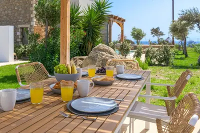 a wooden table with plates of food on it at Villa Elios Mare in Asklipiḯon