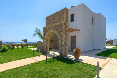 a white house with an arch in a yard at Villa Elios Mare in Asklipiḯon