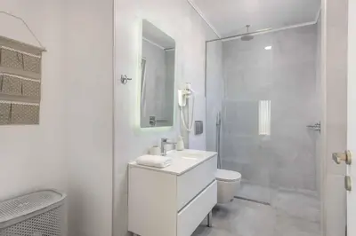 a white bathroom with a sink and a shower at Villa Elios Mare in Asklipiḯon