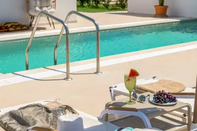 a pool with a table with a plate of grapes and a drink at Villa Elios Mare in Asklipiḯon