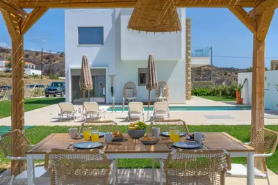 a wooden table and chairs on a patio at Villa Elios Mare in Asklipiḯon